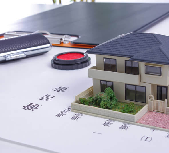 遺言書の紙の上に家の模型とハンコが置いてある写真|北海道札幌の相続不動産買取専門 ご遺族支援 遺品整理 遺言 死後事務委任
